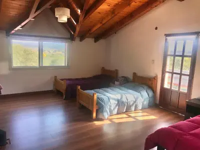 a bedroom with two beds in a room with windows at Cabaña EL GALLO in Villa General Belgrano