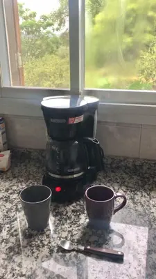 a coffee maker sitting on a counter next to two cups at Cabaña EL GALLO in Villa General Belgrano