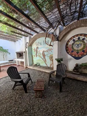 two chairs and a table in a room with a mural at Why Not Guemes in Cordoba