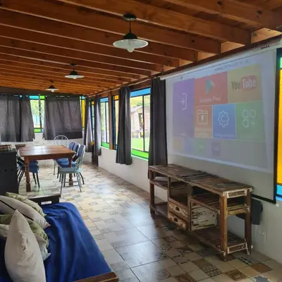 a large projection screen in a room with a table at Casa de campo boutique a 18 minutos de Merlo in Cortaderas