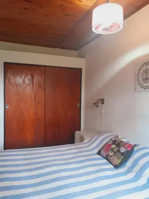 a bedroom with a bed with a blue and white striped blanket at Rakum Apartamentos Turísticos in Villa General Belgrano