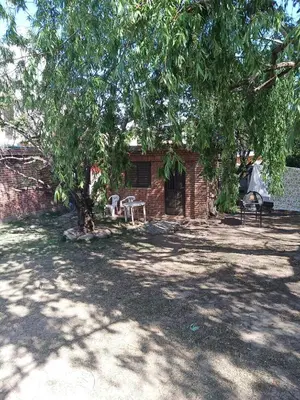 a brick building with two chairs under a tree at Ojos de cielo Monoambientes para 2 y 3 personas in Bialet Massé