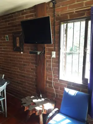 a living room with a tv on a brick wall at Ojos de cielo Monoambientes para 2 y 3 personas in Bialet Massé
