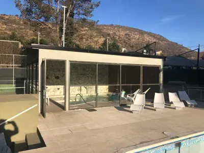 a building with white chairs and a swimming pool at Apart-Hotel Gibert's House in Villa Carlos Paz