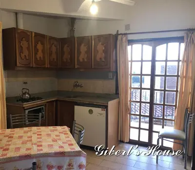 a kitchen with wooden cabinets and a table and a window at Apart-Hotel Gibert's House in Villa Carlos Paz