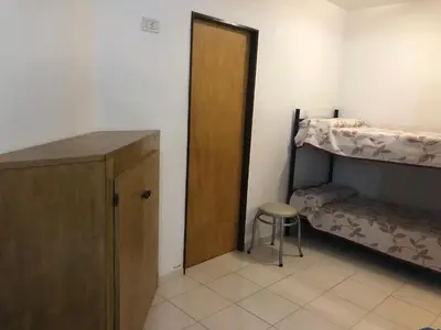 a room with two bunk beds and a door and a stool at Apart-Hotel Gibert's House in Villa Carlos Paz