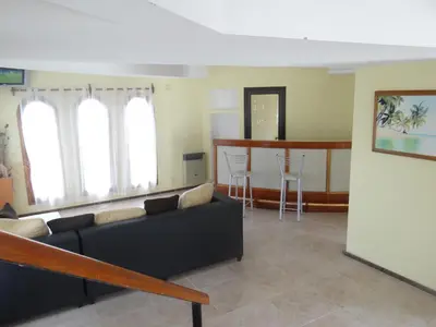 a living room with a couch and a bar at Apart-Hotel Gibert's House in Villa Carlos Paz