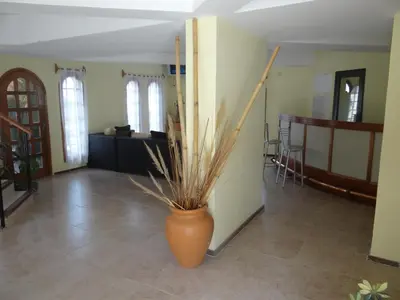 an orange vase with a plant in the middle of a room at Apart-Hotel Gibert's House in Villa Carlos Paz