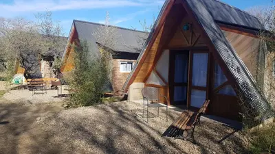a wooden cabin with a bench in front of it at La Estacion in Santa Rosa de Calamuchita