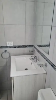 a white bathroom with a sink and a mirror at Ituzaingó 1054 - cochera, pileta y quincho- in Cordoba