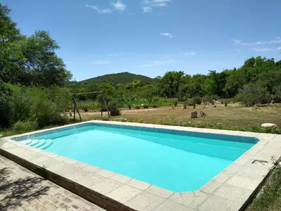 a blue swimming pool in a yard with a playground at TrinidadTraslasierra-CASATUNA in Las Rabonas
