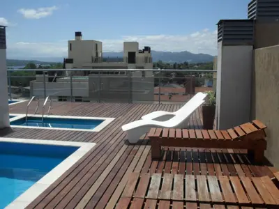 a deck with a bench and a pool on a building at Village Tower in Villa Carlos Paz