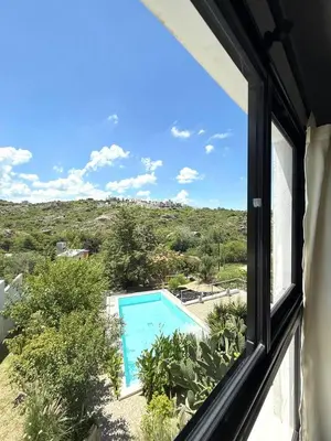 a view of a swimming pool from a window at Sierra Alta Carlos Paz in Villa Carlos Paz