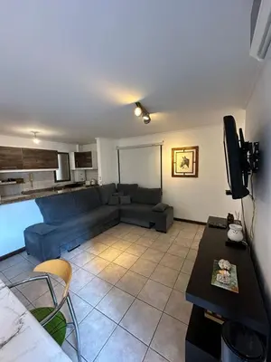 a living room with a blue couch and a tv at Departamento 1 dorm amoblado Nueva Córdoba 6 E INVERHOME INMOBILIARIA in Cordoba