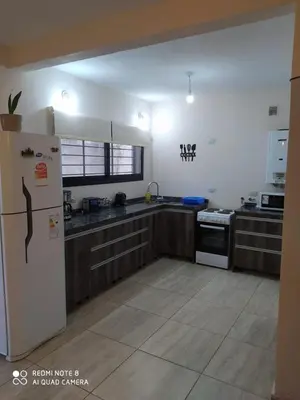 a kitchen with wooden cabinets and a white refrigerator at Casa 3 dormitorios. - Barrio Valle Cercano in Cordoba