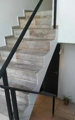 a staircase with wood treads and a black rail at Casa 3 dormitorios. - Barrio Valle Cercano in Cordoba