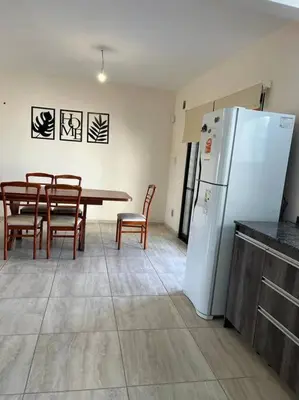 a kitchen with a table and a white refrigerator at Casa 3 dormitorios. - Barrio Valle Cercano in Cordoba