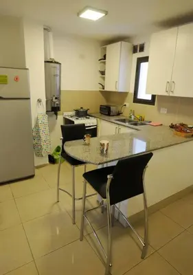 a kitchen with a table and chairs and a refrigerator at Tu lugar en Córdoba. in Cordoba