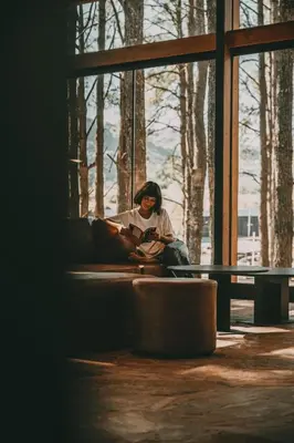a woman sitting in a window reading a book at Get Hotel Molvento, AKEN SOUL Collection in Villa General Belgrano