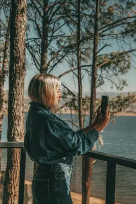 a woman taking a picture of the water with her cell phone at Get Hotel Molvento, AKEN SOUL Collection in Villa General Belgrano