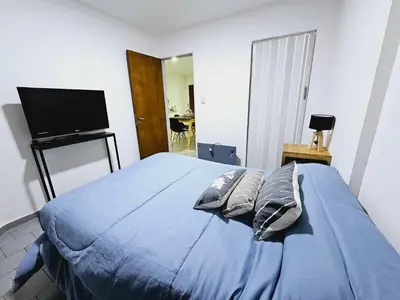 a bedroom with a blue bed with pillows and a flat screen tv at MilcaCeleste Nueva Cordoba II in Cordoba