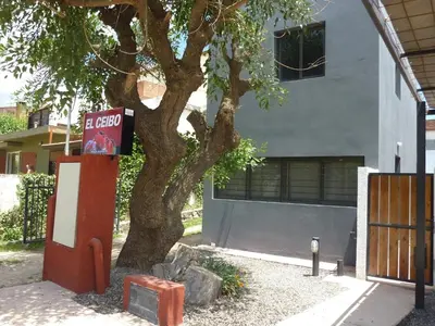 a tree in front of a building with a sign at Dúplex El Ceibo in Villa Carlos Paz