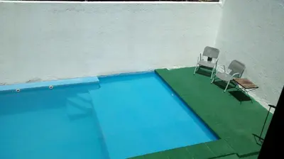two chairs and a swimming pool next to a building at Dúplex El Ceibo in Villa Carlos Paz