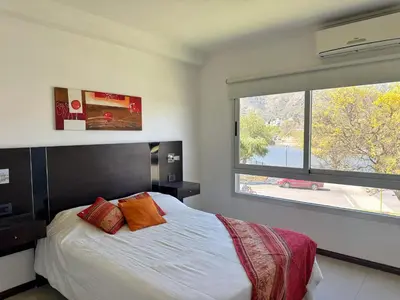 a bedroom with a bed and a large window at Veneto II in Villa Carlos Paz
