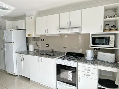 a kitchen with white cabinets and a stove top oven at Veneto II in Villa Carlos Paz