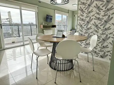 a dining room table with white chairs and a laptop on it at Veneto II in Villa Carlos Paz