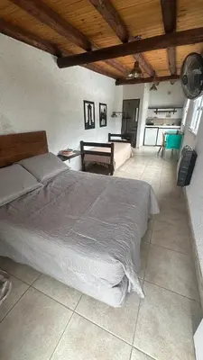 a bedroom with a large bed and a living room at Monoambiente calamuchita in Santa Rosa de Calamuchita