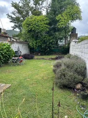 a yard with a retaining wall and a garden with chairs at Monoambiente calamuchita in Santa Rosa de Calamuchita