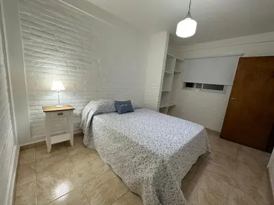 a bedroom with a bed and a table and a lamp at AGRADABLE Dpto. pasaje Tucumán in Alta Gracia