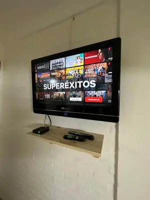 a flat screen tv on a wall with two remote controls at AGRADABLE Dpto. pasaje Tucumán in Alta Gracia