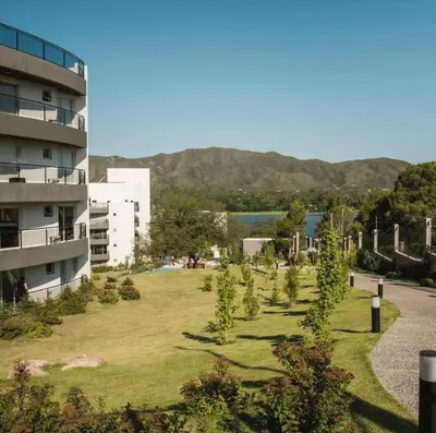 a grassy area with trees in front of a building at Departamento Veneto Village, Parque Siquiman, Carlos Paz in Villa Parque Siquiman