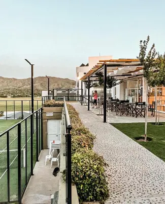 a walkway with a table and chairs and a building at Departamento Veneto Village, Parque Siquiman, Carlos Paz in Villa Parque Siquiman