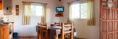 a kitchen with a table and chairs and a television at Estilos Argentinos in Los Reartes