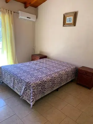 a bedroom with a bed with a purple blanket at Cabañas Susurros del Río in Trapiche