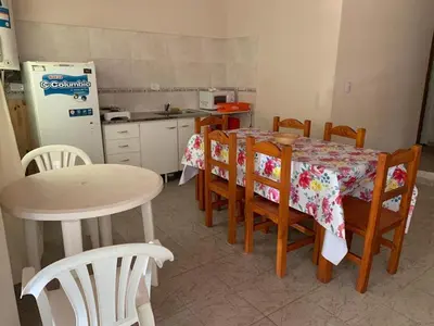 a kitchen with a table and chairs and a refrigerator at Cabañas Susurros del Río in Trapiche