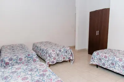 a room with three beds and a wooden cabinet at Cabañas Susurros del Río in Trapiche