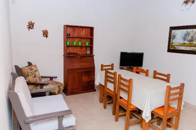 a dining room with a table and chairs and a television at Cabañas Susurros del Río in Trapiche