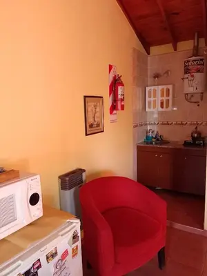 a red chair in a kitchen with a microwave at Aparts Altos del Centro in Merlo