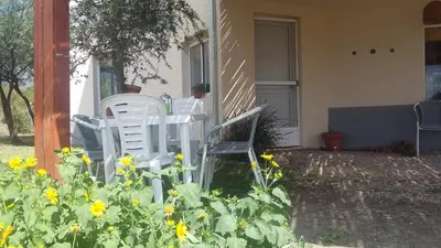two white chairs sitting on the porch of a house with flowers at Sueño del Champaquí in Villa de Las Rosas