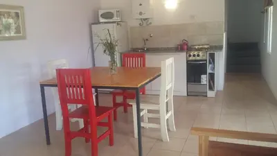a kitchen with a wooden table and red chairs at Sueño del Champaquí in Villa de Las Rosas