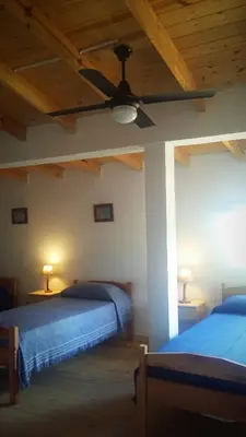 a bedroom with two beds and a ceiling fan at Sueño del Champaquí in Villa de Las Rosas