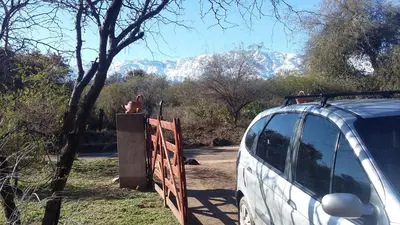 a person sitting on a fence next to a van at Sueño del Champaquí in Villa de Las Rosas