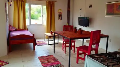 a kitchen with a wooden table and red chairs at Sueño del Champaquí in Villa de Las Rosas