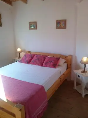 a bedroom with a wooden bed with two tables at Sueño del Champaquí in Villa de Las Rosas