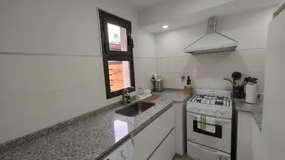 a white kitchen with a stove and a sink at Duplex Zekkei in Villa General Belgrano