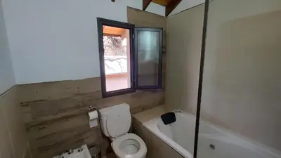 a bathroom with a toilet and a tub and a window at Duplex Zekkei in Villa General Belgrano
